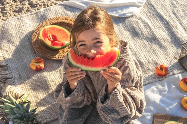 Mała dziewczynka na piaszczystej plaży je arbuza