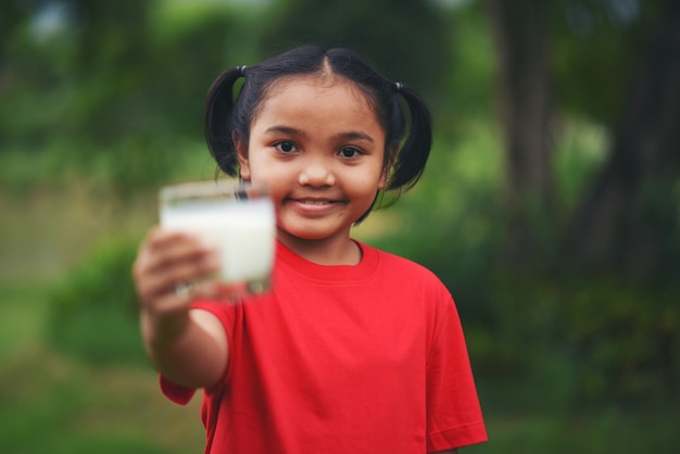 Mała dziewczynka pije mleko w parku