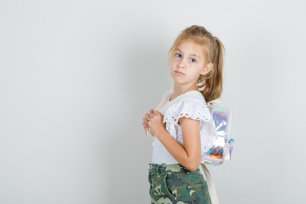 Mała dziewczynka pozuje z plecakiem w białej koszulce