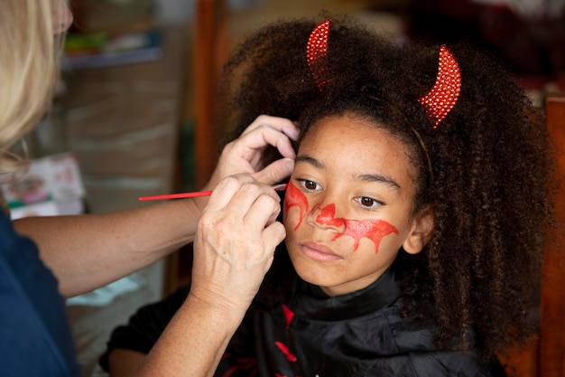 Mała dziewczynka przygotowuje się do Halloween w kostiumie diabła