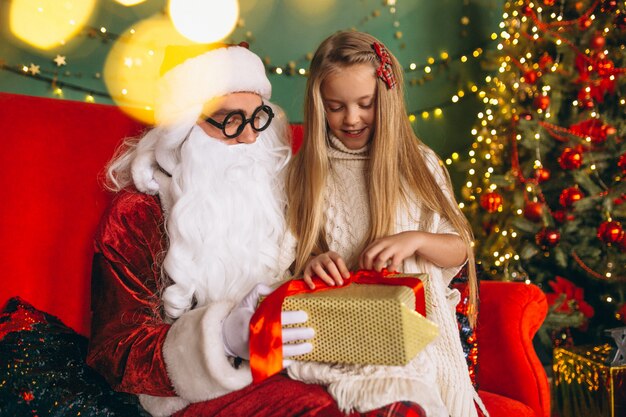 Mała dziewczynka siedzi z santa i prezenty na Boże Narodzenie