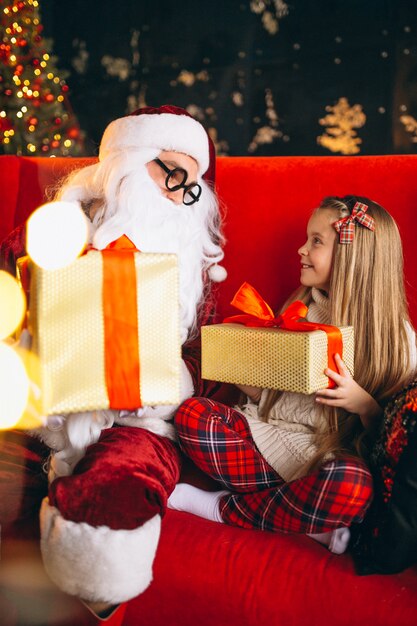 Mała dziewczynka siedzi z santa i prezenty na Boże Narodzenie