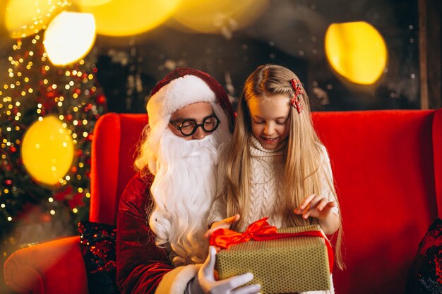 Mała dziewczynka siedzi z santa i prezenty na Boże Narodzenie