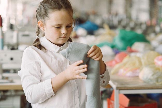 Mała dziewczynka stoi w fabryce z nitką