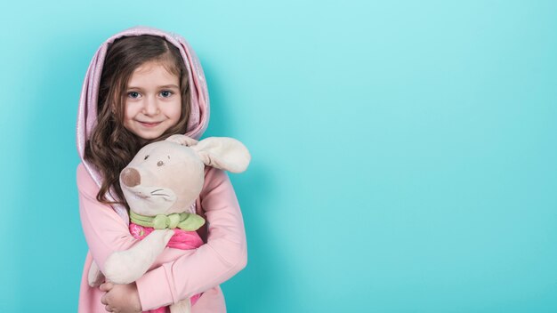 Mała dziewczynka stoi z zabawkarskim królikiem