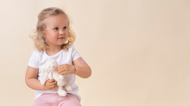 Mała dziewczynka trzyma zabawkę po otrzymaniu szczepionki