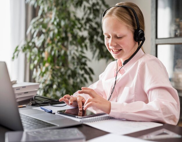 Mała dziewczynka uczestnicząca w zajęciach online podczas korzystania z tabletu