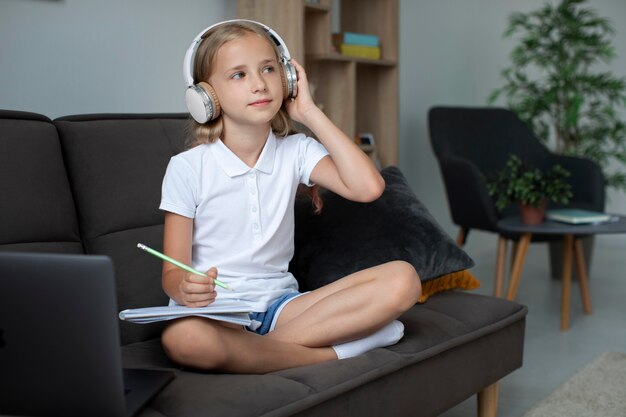 Mała dziewczynka uczestnicząca w zajęciach online podczas korzystania ze słuchawek