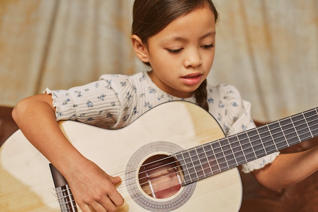 Mała dziewczynka uczy się grać na gitarze w domu