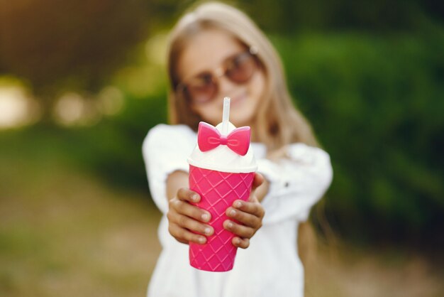 Mała dziewczynka w parkowej pozyci z różową filiżanką