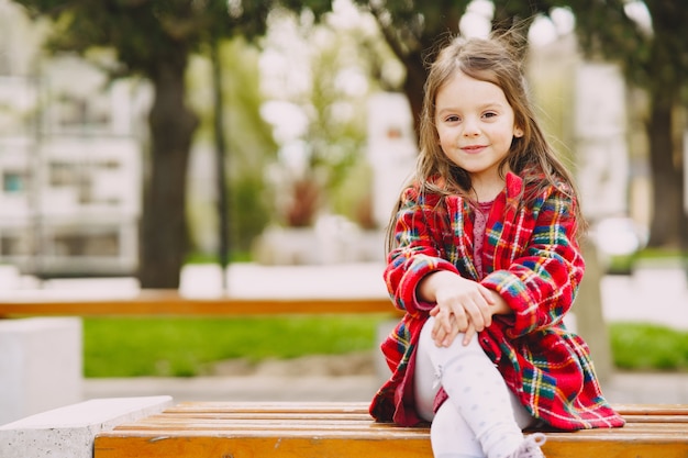 Mała dziewczynka w parkowym obsiadaniu na ławce