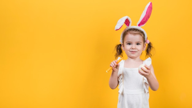 Bezpłatne zdjęcie mała dziewczynka w uszy królika z jajkiem i filcu pióra