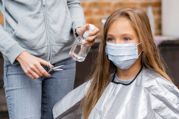 Bezpłatne zdjęcie mała dziewczynka z maską medyczną u fryzjera