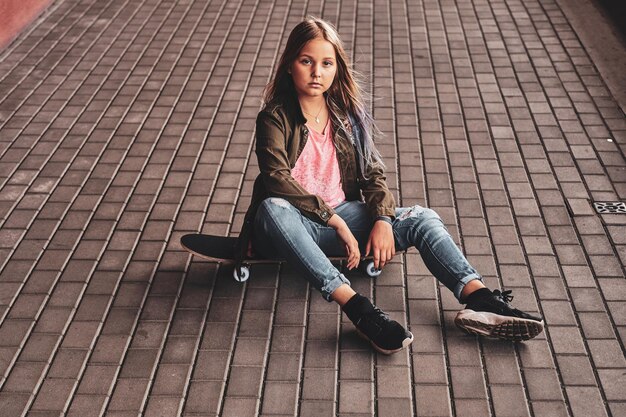 Mała ładna nastolatka siedzi na podłodze, pozując dla fotografa w tunelu.