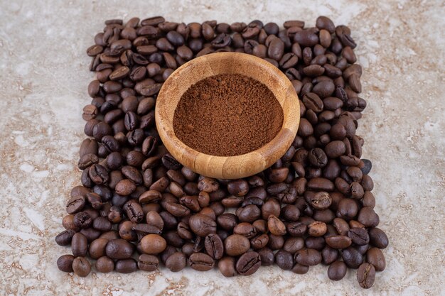 Mała miska z kawą w proszku otoczona małym stosem ziaren kawy