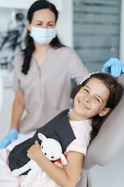 Mała piękna dziewczyna u dentysty, patrząc i uśmiechając się