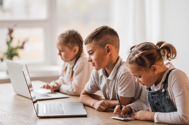 Małe dzieci korzystające z laptopów w szkole