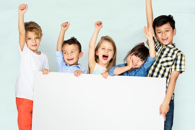 Bezpłatne zdjęcie małe dzieci wiwatujące, trzymając białą tablicę