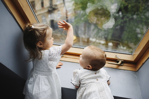 Małe dzieci wyglądają przez okno