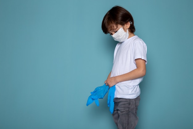 Małe dziecko w białej sterylnej masce ochronnej i niebieskich rękawiczkach jako środek ochronny przed koronawirusem na niebiesko