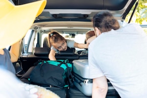 Małe dziecko w samochodzie wyjeżdżającym na wakacje z rodzicami i dziadkami, ładowanie toreb podróżnych w bagażniku samochodu. duża szczęśliwa rodzina podróżująca na wakacjach, aby udać się do nadmorskiego miejsca.