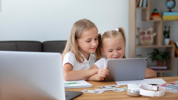 Małe dziewczynki robią razem szkołę online w domu