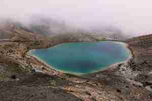 Bezpłatne zdjęcie małe jezioro na środku pustyni w pobliżu góry w mglisty dzień