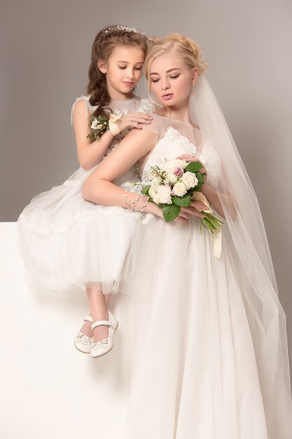 Małe ładne dziewczynki z kwiatami ubrane w suknie ślubne