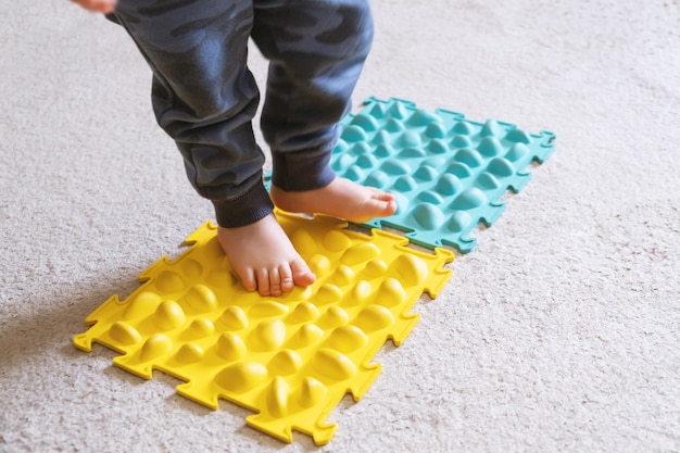Bezpłatne zdjęcie małe stopy dziecka na prążkowanym dywanie.