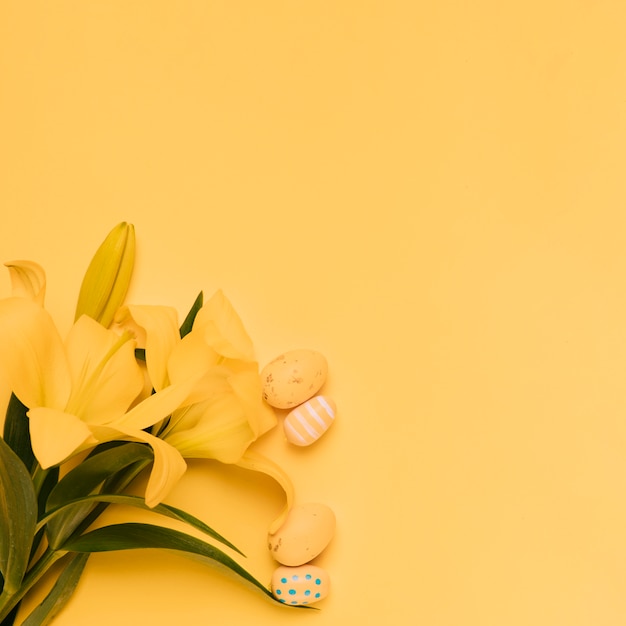 Bezpłatne zdjęcie mali easter jajka z piękną żółtą lelują kwitną na żółtym tle