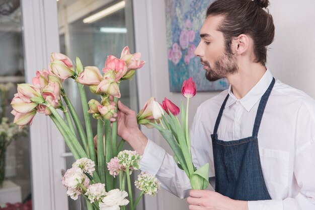 Mały biznes. Mężczyzna kwiaciarnia w kwiaciarni. wykonywanie dekoracji i aranżacji