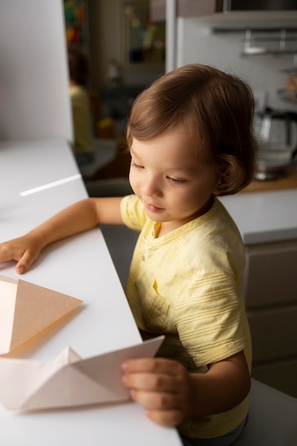 Bezpłatne zdjęcie mały chłopiec bawi się papierem origami w domu