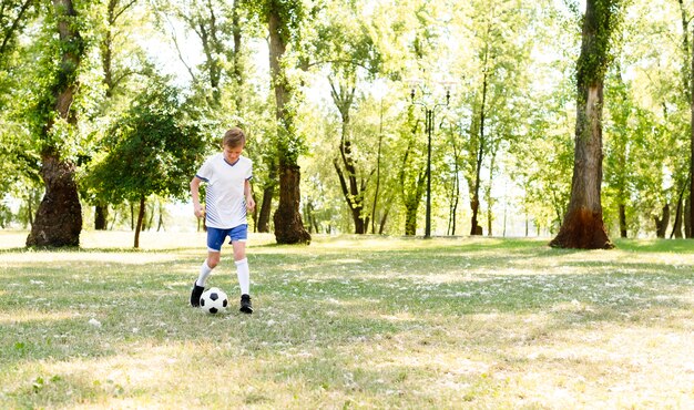 Mały chłopiec gra w piłkę nożną sam z miejsca na kopię
