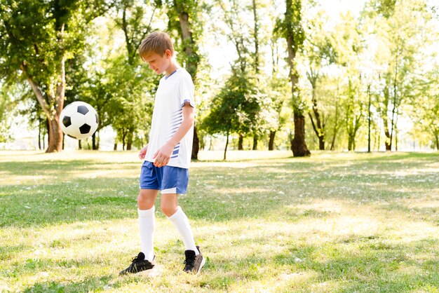 Mały chłopiec gra w piłkę nożną z miejsca na kopię