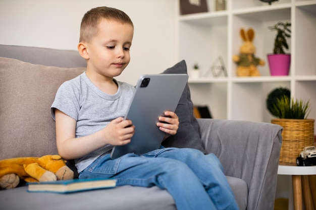 Bezpłatne zdjęcie mały chłopiec patrzący na swój tablet