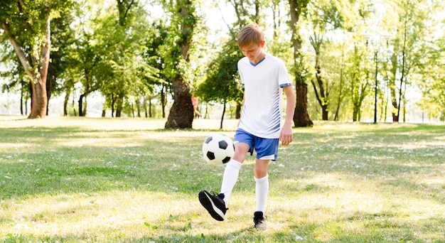 Mały chłopiec sam gra w piłkę nożną