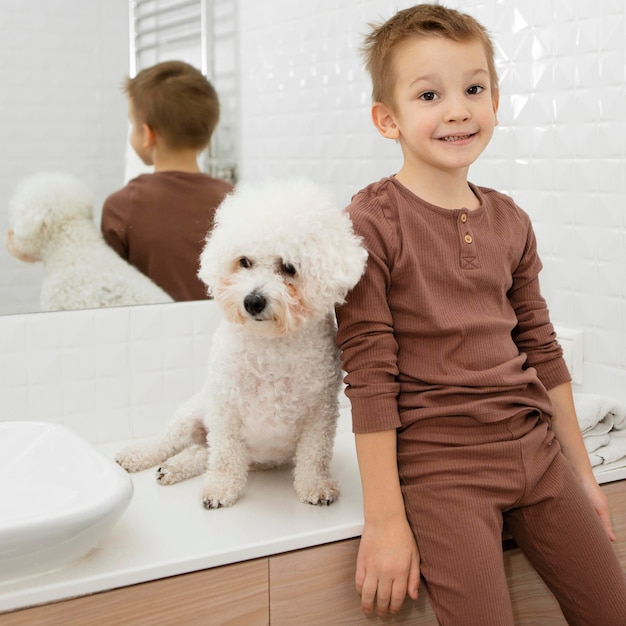 Mały chłopiec siedzi obok swojego psa w łazience