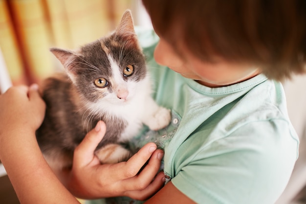 Mały chłopiec trzyma czarno-białe kitty na ramieniu