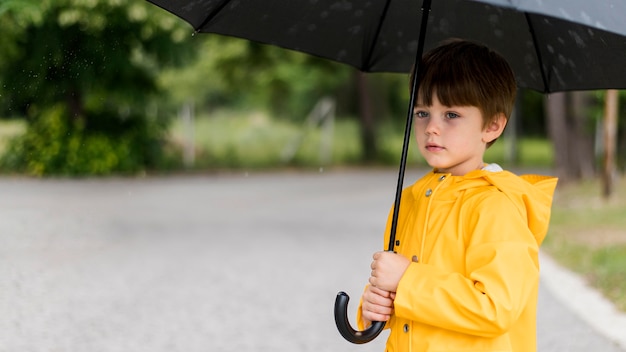 Mały chłopiec trzyma parasol z miejsca na kopię