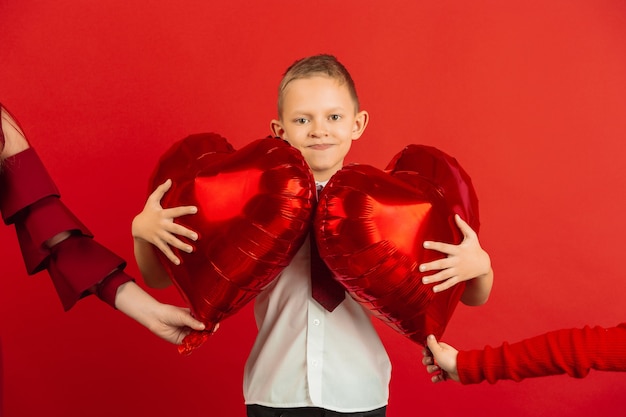 Mały chłopiec trzymając czerwone balony w kształcie serca