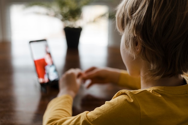 Bezpłatne zdjęcie mały chłopiec za pomocą smartfona w domu