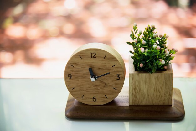 Mały drewniany zegar z dekorowanym zestawem kwiatowym