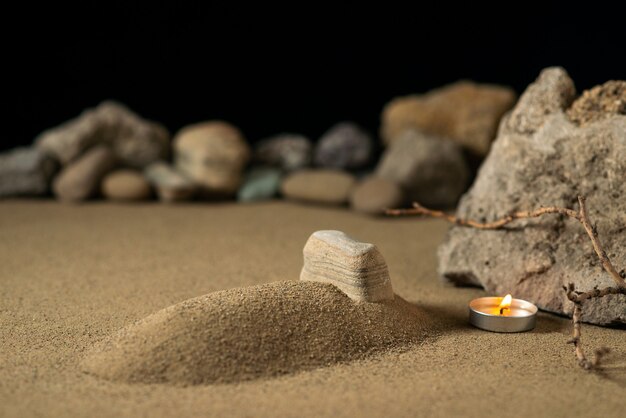 Mały grób ze świecą i kamieniami na wojnie pogrzebowej piasku