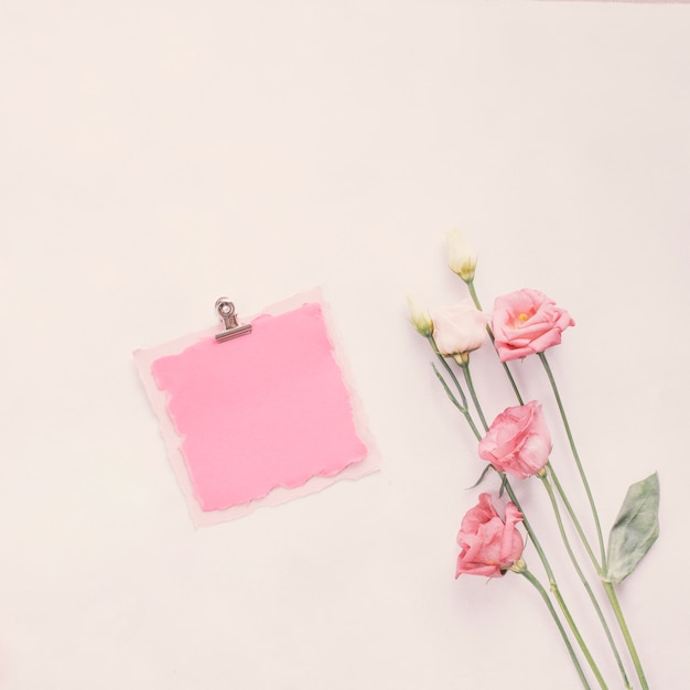Bezpłatne zdjęcie mały pusty papier z jaskrawymi kwiatami na stole