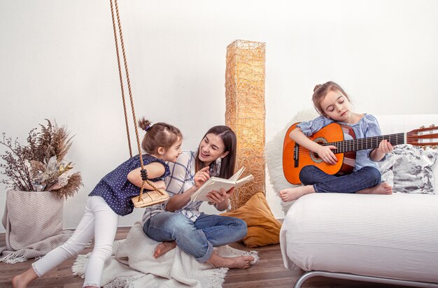 Mama bawi się z córkami w domu. Lekcje na instrumencie muzycznym, gitarze. Pojęcie przyjaźni i rodziny dzieci.