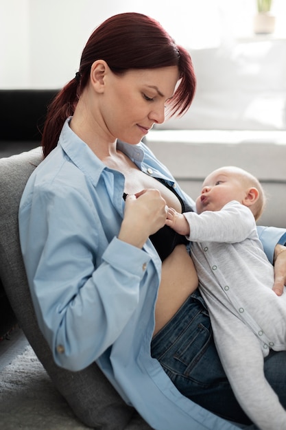 Bezpłatne zdjęcie mama delikatnie karmi dziecko piersią