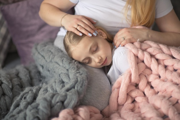 Mama i córka blondyna śpią na łóżku