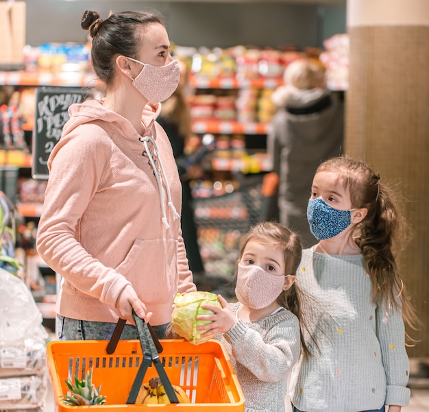 Mama i córki robią zakupy w maskach w sklepie podczas kwarantanny z powodu pandemii koronawirusa.