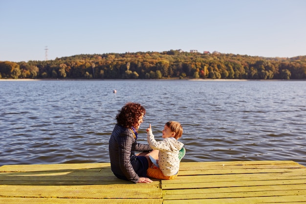 Bezpłatne zdjęcie mama i syn odpoczywa nad jeziorem