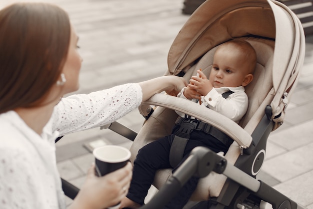 Mama Siedzi Na ławce. Kobieta Pchająca Swojego Malucha Siedzącego W Wózku. Koncepcja Rodziny.